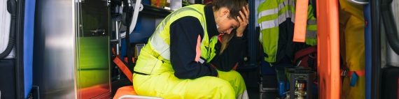 Paramedic in back of ambulance with face in hands